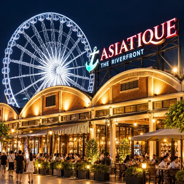 ป้าย ASIATIQUE THE RIVERFRONT และชิงช้าสวรรค์ประดับไฟยามค่ำคืน เหนืออาคารร้านอาหารและทางเดินที่มีผู้คน