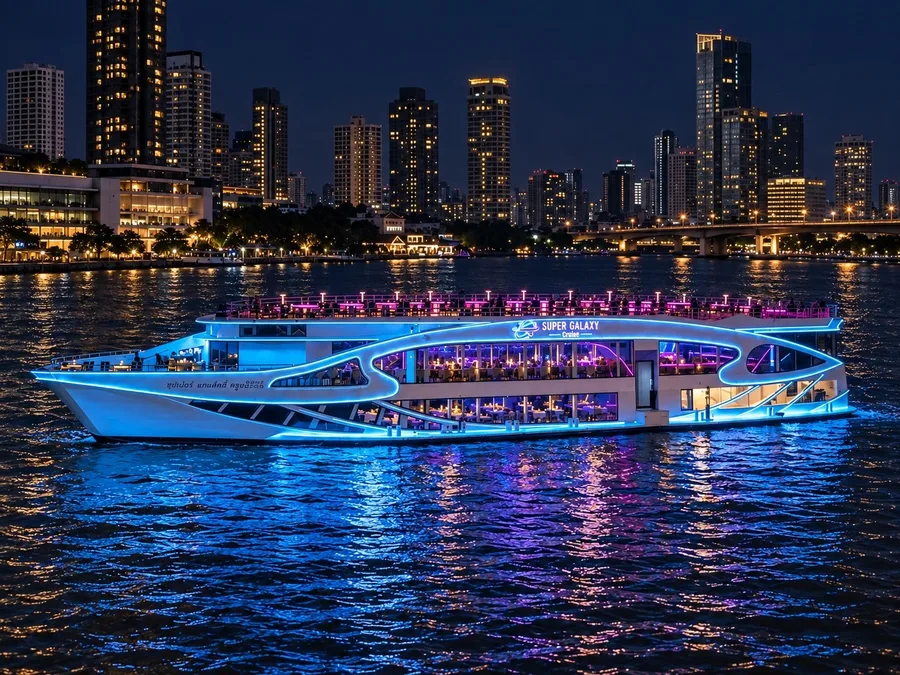 เรือ Super Galaxy Cruise ประดับไฟสีฟ้าและชมพูบนแม่น้ำเจ้าพระยา มีดาดฟ้าเปิดโล่งและอาคารริมแม่น้ำเป็นฉากหลังยามค่ำคืน