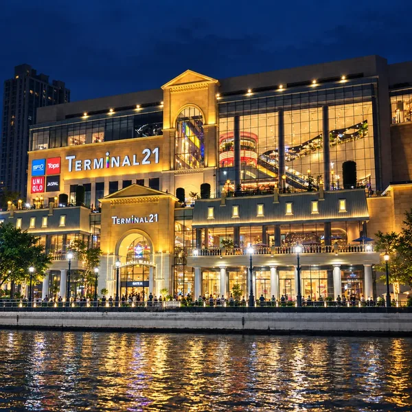 อาคาร Terminal 21 พระราม 3 ริมแม่น้ำประดับไฟสีทองยามค่ำคืน มีแสงสะท้อนบนผิวน้ำ