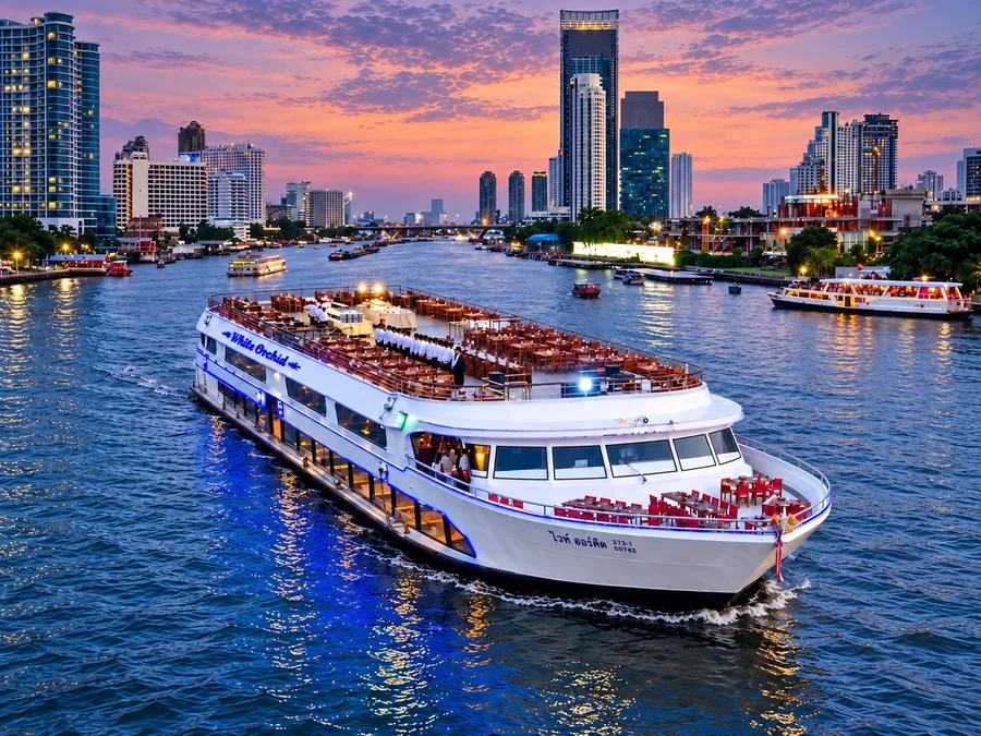 เรือ White Orchid River Cruise รอบ Twilight บนแม่น้ำเจ้าพระยา เห็นโต๊ะอาหารบนดาดฟ้าเปิดโล่งใต้ท้องฟ้าสีชมพูส้มยามเย็น